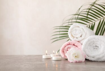 Towels, candles and flower on grey background, space for text